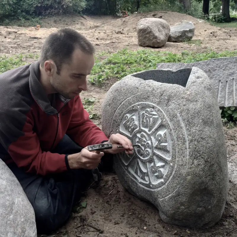 Zīmju akmens ar iegravētiem budistu simboliem šoreiz vāzes interpretācijā