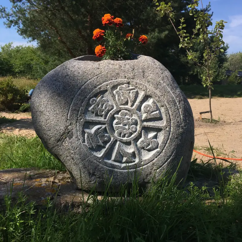 Puķu akmens ar Budistu mantru, kur aplis simbolizē dzīves mūžību cikliskumu