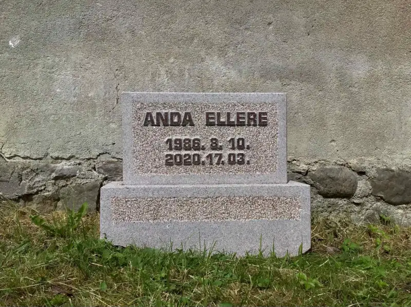 No Latvijas akmens gatavota uzraksta plāksne lauku kapos.