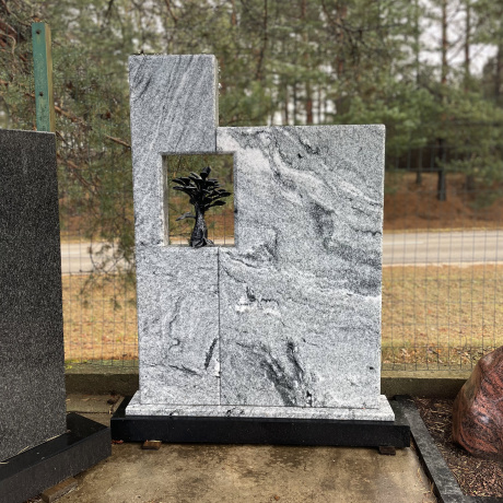 Gaiši pelēks granīta kapu piemineklis ar kaltu dekoratīvu koku taisnstūra atvērumā