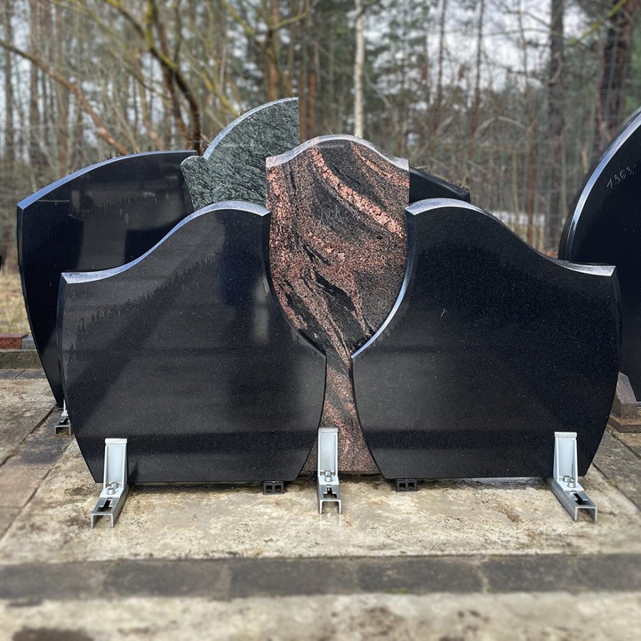 Dubultais kapu piemineklis no divām melna izliektu granīta plāksnēm ar sarkana granīta plāksni centrā