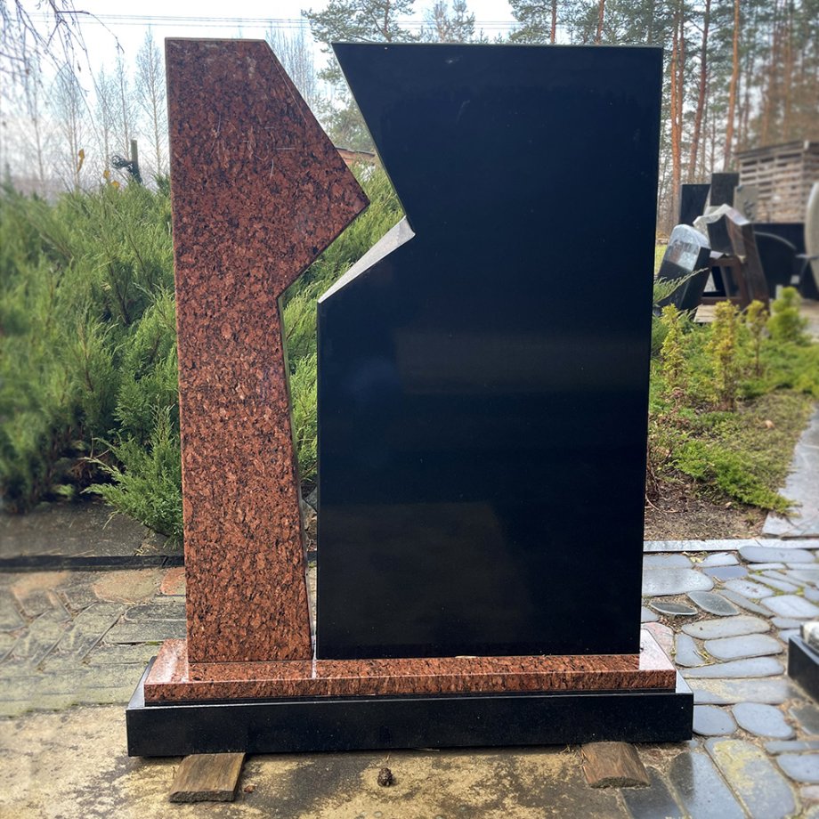 Vertikāls taisnstūrveida kapu piemineklis kur asā līnija atdala melno un sarkano granītu