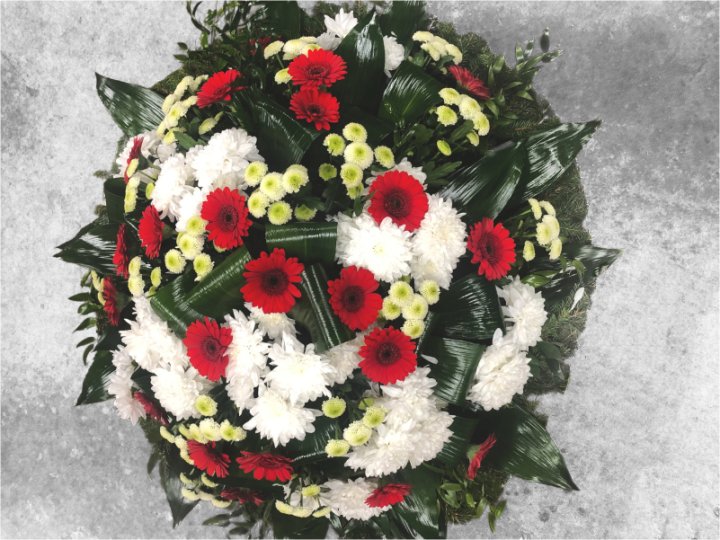 Funeral wreath of red gerberas, white chrysanthemums, and yellow-white small-flowered chrysanthemums
