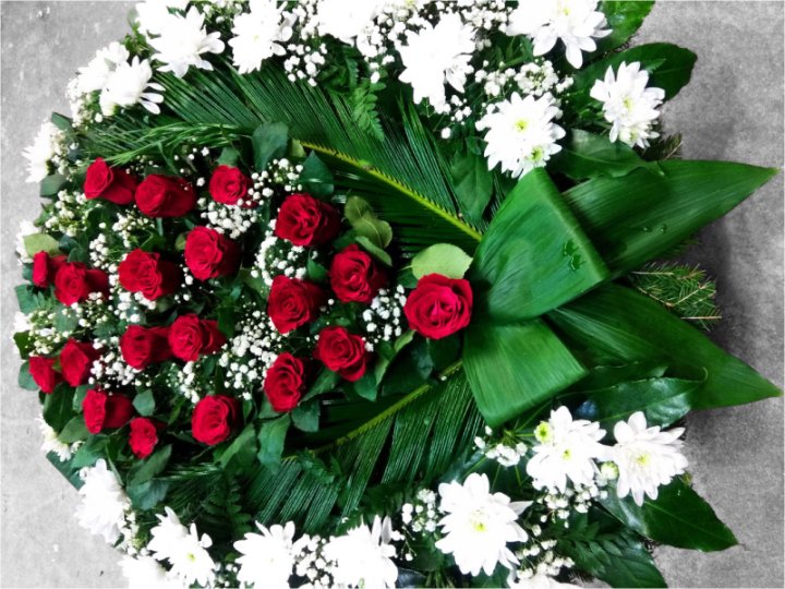 Funeral wreath made of vibrant red roses and white chrysanthemums
