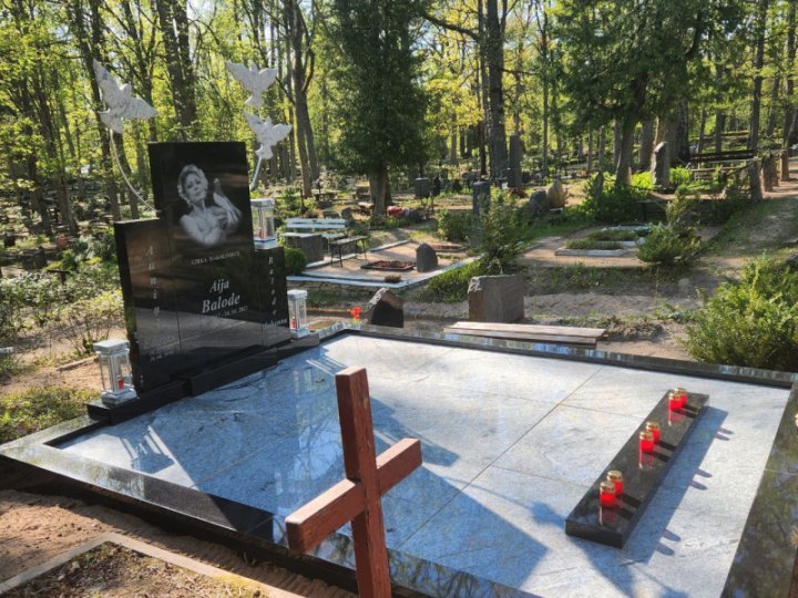 Grave monument ensemble with stone birds, candle holders, and a portrait