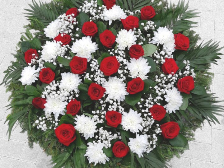 A funeral wreath with fresh roses and chrysanthemums on a natural fir base